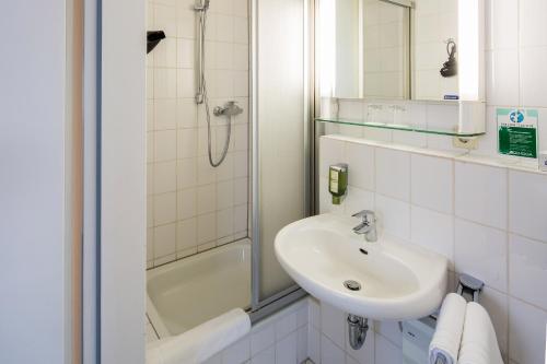 a white bathroom with a sink and a shower at Central Hotel in Mannheim