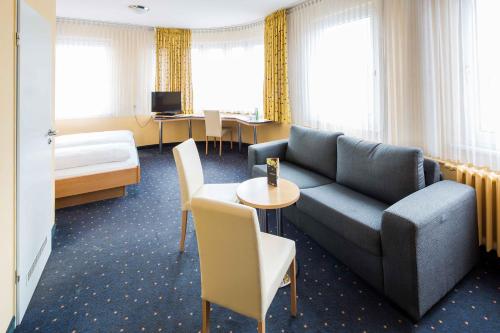 a hotel room with a couch and a bed and a table at Central Hotel in Mannheim