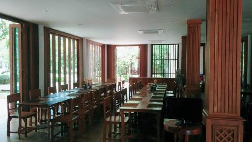 un comedor con mesas y sillas de madera y ventanas en Anyamanee Resort, en Cha Am