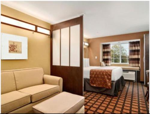 a hotel room with a bed and a couch at Microtel Inn & Suites by Wyndham Ozark in Ozark