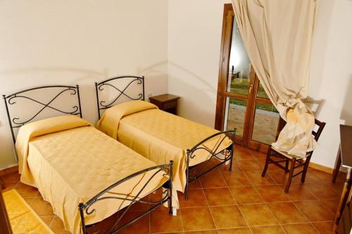 a bedroom with two beds and a chair and a window at Monte Pirastru in Nughedu San Nicolò