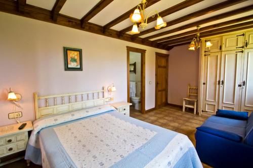 - une chambre avec un grand lit et un canapé bleu dans l'établissement Hospedaje Granada, à San Vicente de la Barquera