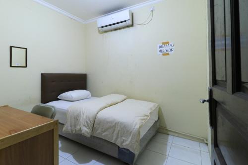een kleine kamer met een bed, een bureau en een deur bij Guest House Samarinda in Samarinda