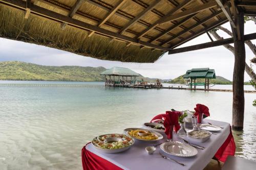 a table with food on it next to a body of water at La Estancia Busuanga in Busuanga