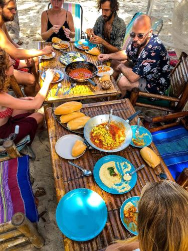een groep mensen die rond een tafel zitten met eten bij Colorful Hut in Haad Pleayleam