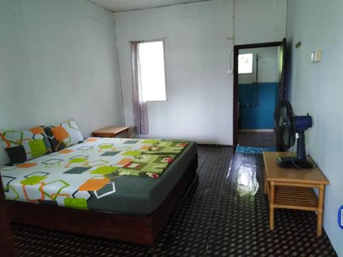 Schlafzimmer mit einem Bett, einem Tisch und einem Fenster in der Unterkunft AA Homestay in Gunung Mulu Nationalpark