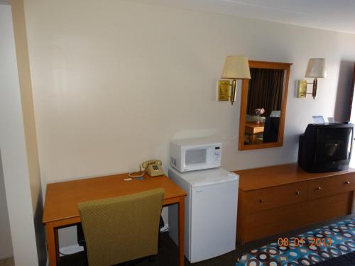 a hotel room with a desk and a microwave at Colony Motel in Brookfield