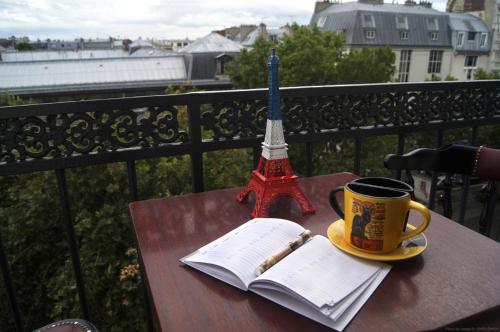a table with a book and a pen and a cup of coffee at Hotel Regina Montmartre in Paris