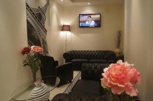 a living room with a couch and a tv on a wall at Hotel Regina Montmartre in Paris