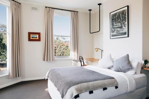 a white bedroom with a bed and a window at Naughtons Hotel in Melbourne