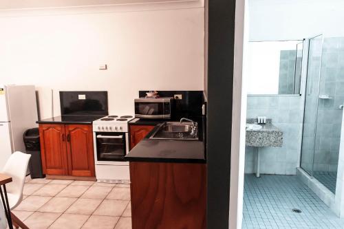 a kitchen with a sink and a microwave at Motel Nomad in Cairns