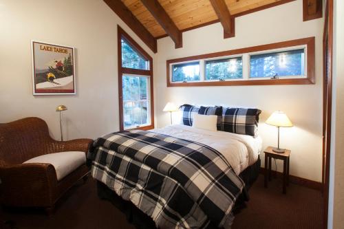 ein Schlafzimmer mit einem Bett und einem Stuhl sowie zwei Fenstern in der Unterkunft Luxury Lodgepole Home at Northstar in Truckee