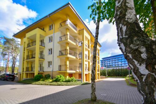 ein gelbes und weißes Gebäude mit einem Baum in der Unterkunft Apartamenty na Wyspie - Villa Park - Parking in Świnoujście