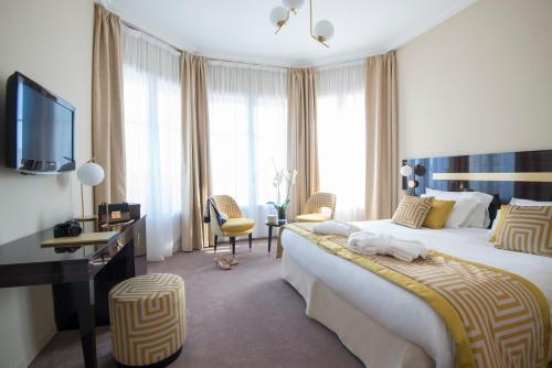 una camera d'albergo con un grande letto e una TV di Hotel Carlton a Beaulieu-sur-Mer