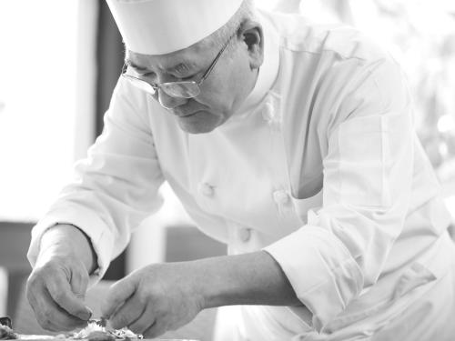 a man in a chefs hat preparing food in a kitchen at Hotel Palm Royal Resort Kokusai Street in Naha