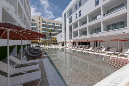 a swimming pool with chairs and umbrellas next to a building at Kokkinos Boutique Hotel in Protaras