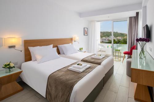 a hotel room with two beds and a large window at Kokkinos Boutique Hotel in Protaras