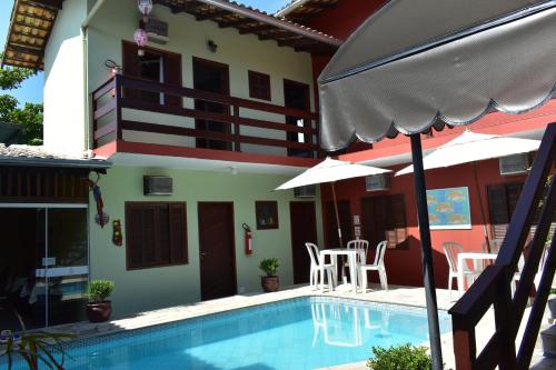 a house with a swimming pool with chairs and an umbrella at Pousada Cores Do Mar in Paraty