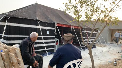 two men sitting in chairs in front of a tent at Khan Alsira - חאן אלסרה in Alsira