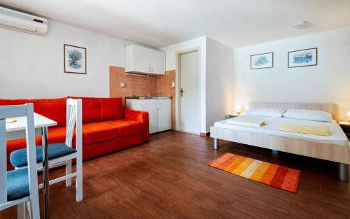 a living room with a bed and a red couch at Apartments Sentic in Neum
