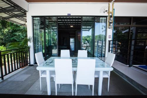 a white dining table and white chairs on a balcony at Blue Moon Design House in Ko Samed
