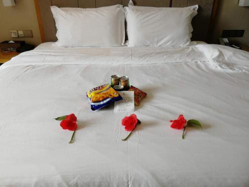 a white bed with red flowers on it at Lavande Hotel Shantou Chenghai Branch in Shantou