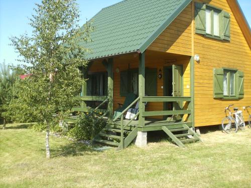 a large wooden house with a porch and a tree at Domek "U Magdy" in Sasino