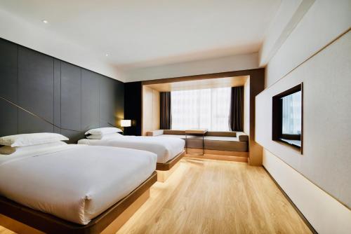 a hotel room with two beds and a window at Haikou S-INN Hotel in Haikou
