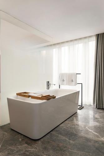 a white bath tub in a room with windows at Haikou S-INN Hotel in Haikou