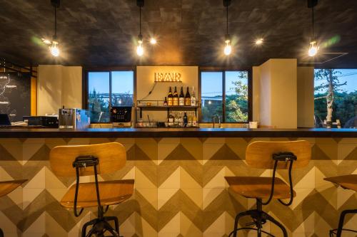 - un bar avec des tabourets en bois dans un restaurant dans l'établissement I-Link Hostel & Cafe Shimanami, à Imabari