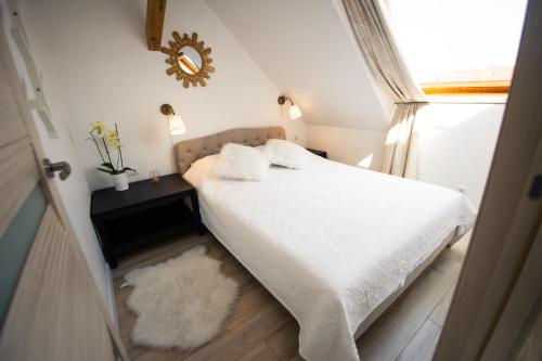 a bedroom with a bed with white sheets and a mirror at Apartamentai Niden - su terasa ir vaizdu i marias Nidos centre in Nida
