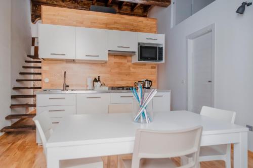 a white kitchen with a white table and chairs at Casa Romeo in Cuneo
