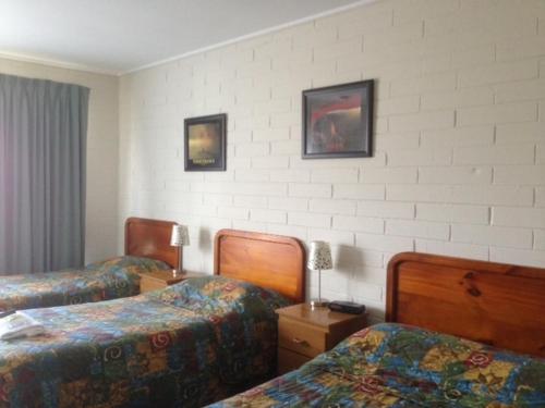 a hotel room with two beds and two lamps at Gisborne Motel in Gisborne