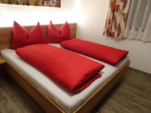 a bed with red pillows on top of it at Haus Höll Herta in Hallstatt