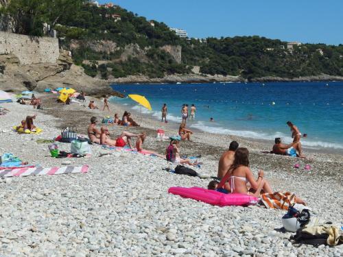 a group of people sitting on a rocky beach at Résidence "Le Golfe Bleu" in Roquebrune-Cap-Martin