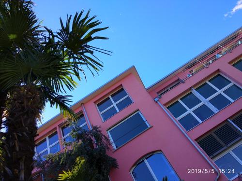 a pink building with palm trees in front of it at Residence Venus Garden in Brissago