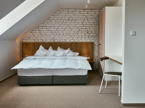 a bedroom with a large bed with a brick wall at Hotel a Hostinec Slunce in Osečná