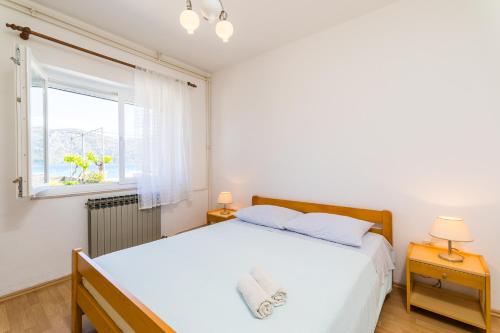 a bedroom with a large white bed and a window at Apartment Kneže in Račišće