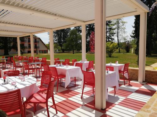 a dining area with white tables and red chairs at Les Maritonnes Parc & Vignoble in Romanèche-Thorins