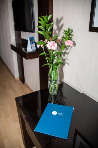 a vase with flowers on a table with a blue card at Oh Nice Ulises Ceuta in Ceuta