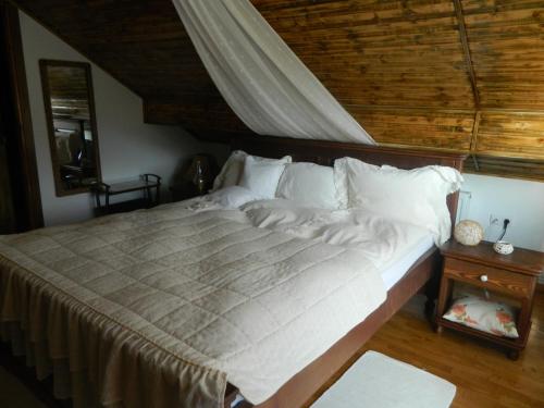 a large bed in a bedroom with a wooden ceiling at Pensiunea Romantic in Sadu