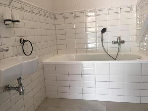 a white tiled bathroom with a tub and a sink at Malinowe Wzgórze domki 90 m2 z sauną i balią in Krzeszna