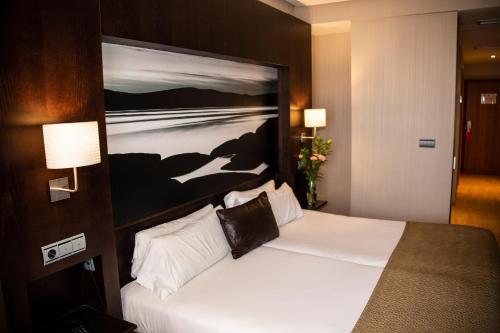 a hotel room with a bed with a painting on the wall at Oh Nice Ulises Ceuta in Ceuta