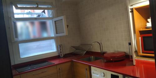 a kitchen with a sink and a red counter top at KosmeEtxea, la casa del Parque EBI727 in Bermeo