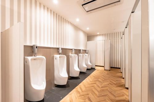 a row of white urinals in a bathroom at I-Link Hostel & Cafe Shimanami in Imabari