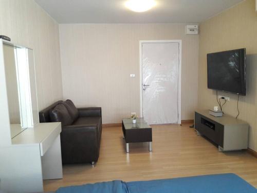 a living room with a couch and a flat screen tv at Plum Phahol89, Prachathipat in Ban Talat Rangsit