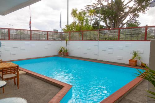 a swimming pool in a patio with a table and chairs at New Haven Motel in Auckland