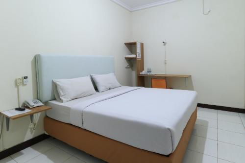 een wit bed in een kamer met een telefoon bij Hotel Celia in Samarinda