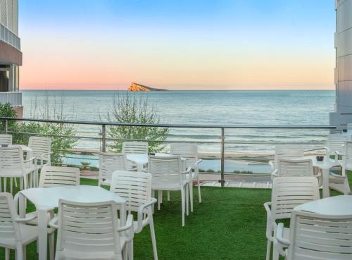 un balcón con sillas y mesas blancas y el océano en Hotel RH Corona del Mar 4* Sup, en Benidorm