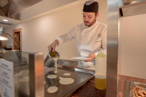 
a man in a kitchen preparing food in a kitchen at Hotel RH Corona del Mar 4* Sup in Benidorm
